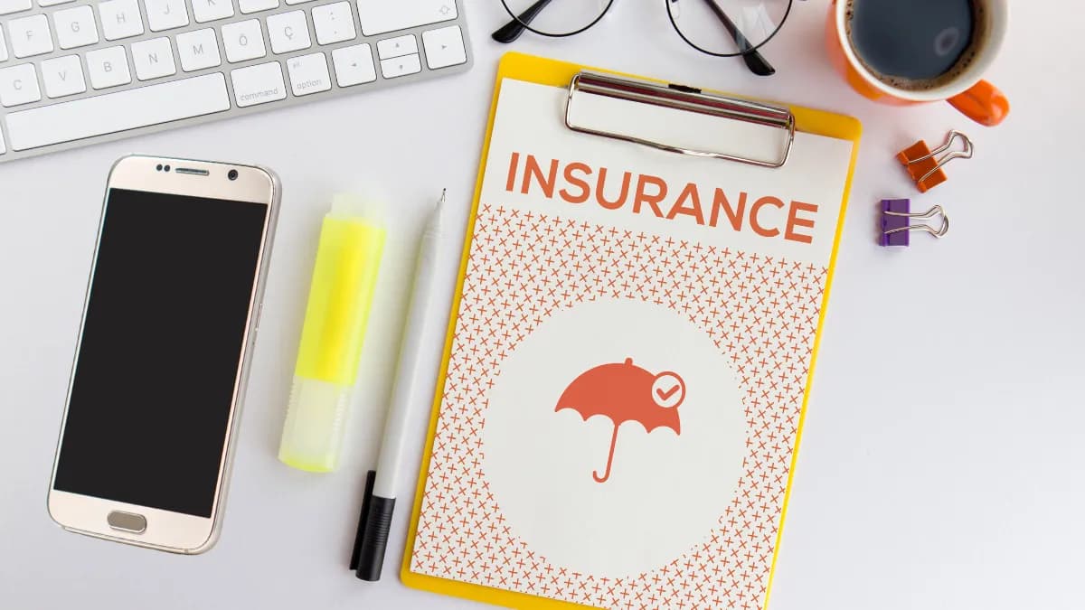 un téléphone portable à côté d'un bloc-notes sur lequel est écrit « Assurance »