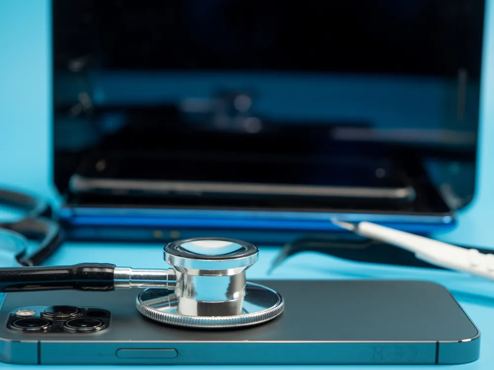 stéthoscope posé sur un téléphone portable près d'un ordinateur de bureau