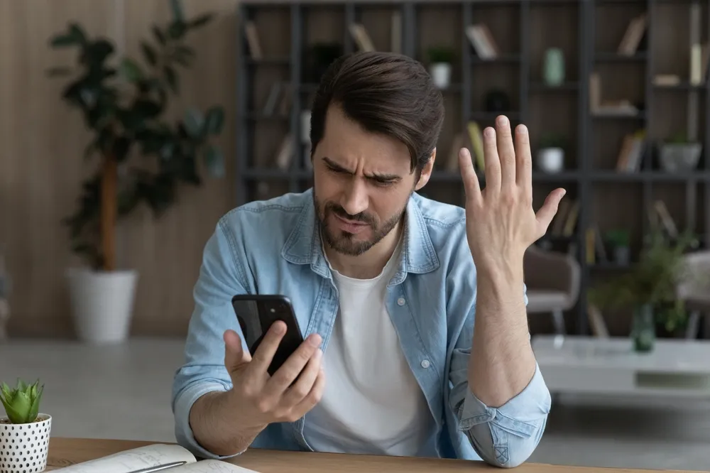 un homme déconcerté par son téléphone portable