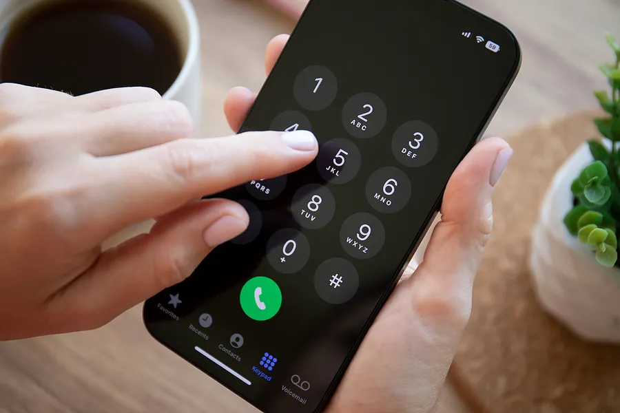 Doigt appuyant sur les touches d'un iPhone 14