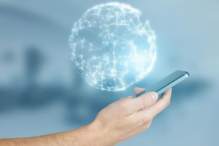 Une main tenant un iPhone surmonté d'une planète