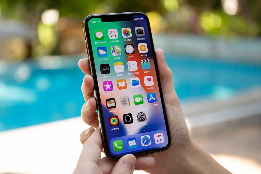 Une main tenant un iPhone à l'extérieur pour montrer ce qu'est la fonction True Tone sur l'iPhone.