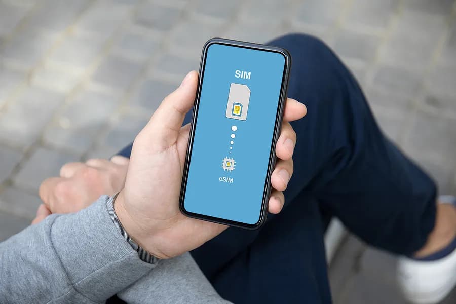 Personne assise, les jambes croisées, tenant un téléphone portable
