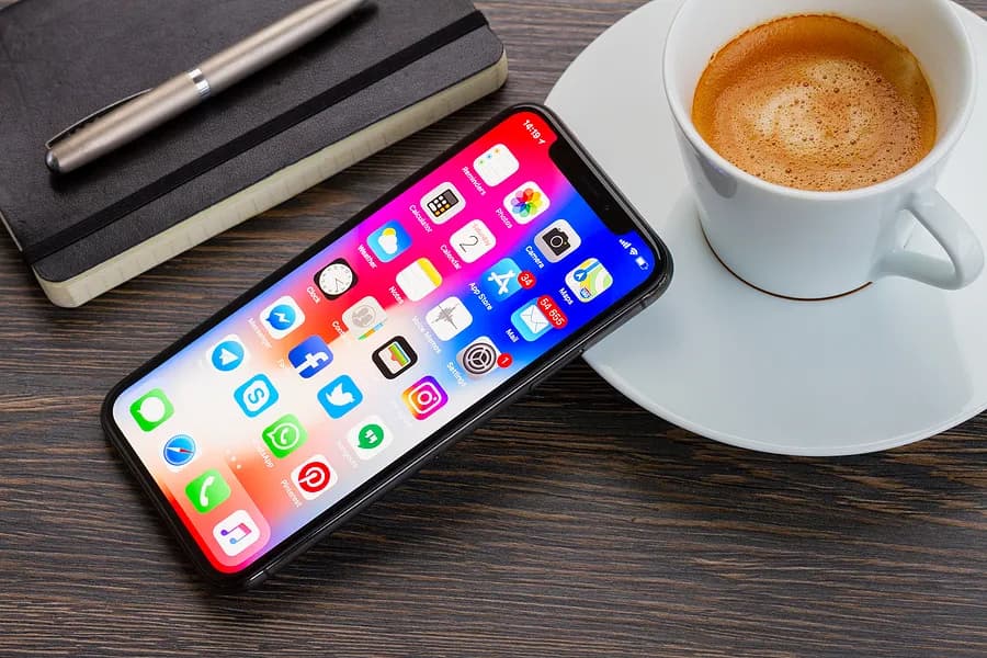 Un iPhone posé contre une tasse de café