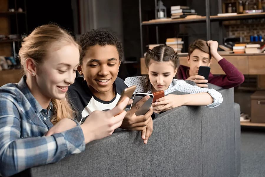 Quatre adolescents regardant leur téléphone portable.