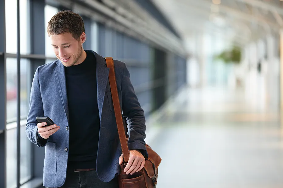 Un homme marchant, son téléphone à la main.