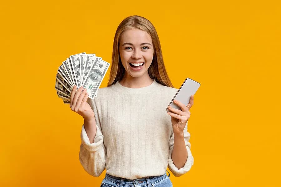 Une femme tenant un téléphone et de l'argent.