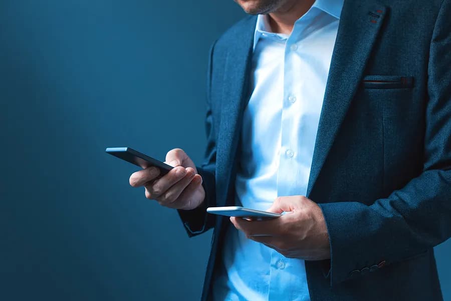 Un homme tenant deux téléphones.