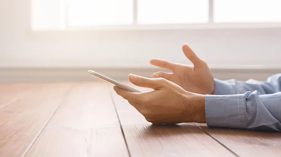 Personne tenant un iPhone près d'une fenêtre, illustrant comment déverrouiller l'iPhone à l'aide du code d'accès sans ordinateur.