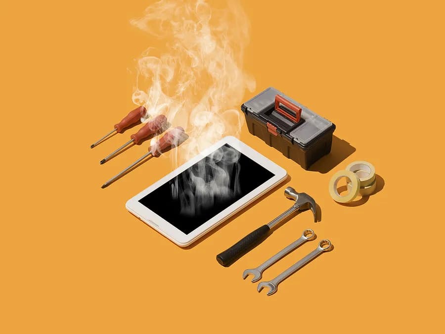 Un smartphone d'où s'échappe de la fumée repose sur une surface orange, entouré d'outils de réparation, notamment des tournevis, des clés, un marteau, du ruban adhésif et une petite boîte à outils, symbolisant la surchauffe du téléphone et sa réparation.